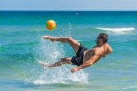 Man kicking a ball in the surf